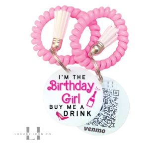 I'm the Birthday Girl Buy me a Drink Bracelet with QR code on back for scanning attached to pink coil bracelet with white tassel. By Luxury Icon Co.