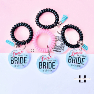 pink and blue bachelorette party bride bracelet featuring "She Found Her Lover Buy Me A Drink" in black lettering and clouds. The bracelet is waterproof and designed for easy scanning with Venmo and other payment apps. By Luxury Icon Co.